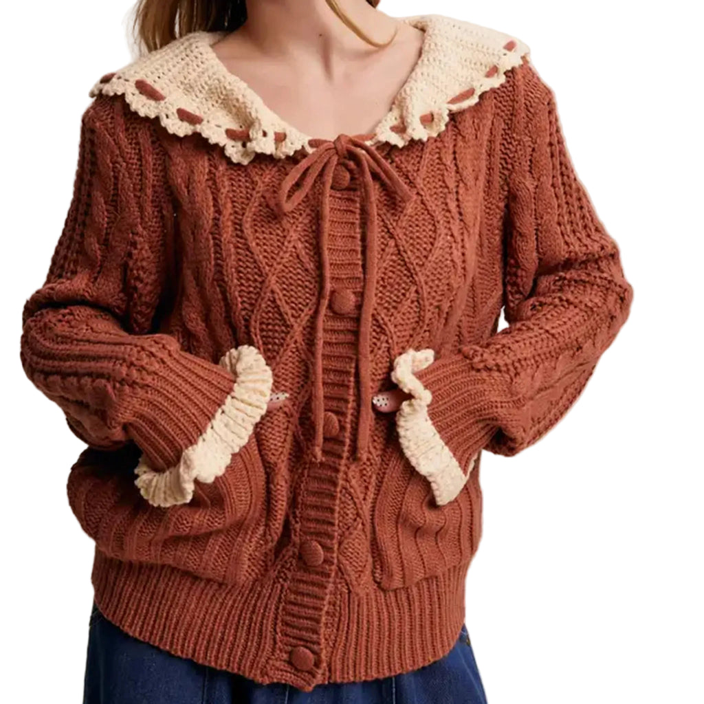 Model wearing dark orange knit sweater with cream colored frilled cuffs and cream colored layover collar. 