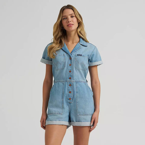 Model wearing a Wrangler women’s denim snap utility romper with short sleeves, snap‑front closure, and Western utility pockets.