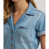 Close‑up of model wearing a Wrangler women’s denim snap utility romper showing the snap‑front placket, utility chest pockets, and denim texture.