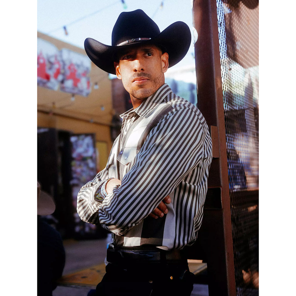 Side view of a model in the Wrangler black and gray Brushpopper shirt, highlighting the sleeve shape, stripe layout, and relaxed Western silhouette.