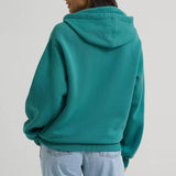 Back view of a model wearing the turquoise Wrangler logo hoodie, showing the plain back.