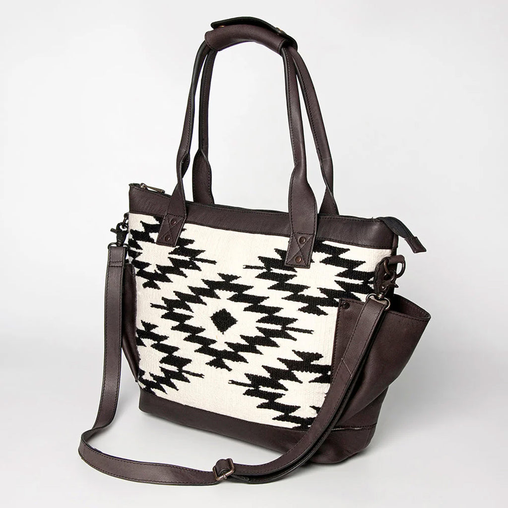 Black and white Aztec purse with dark brown leather pockets and straps. 