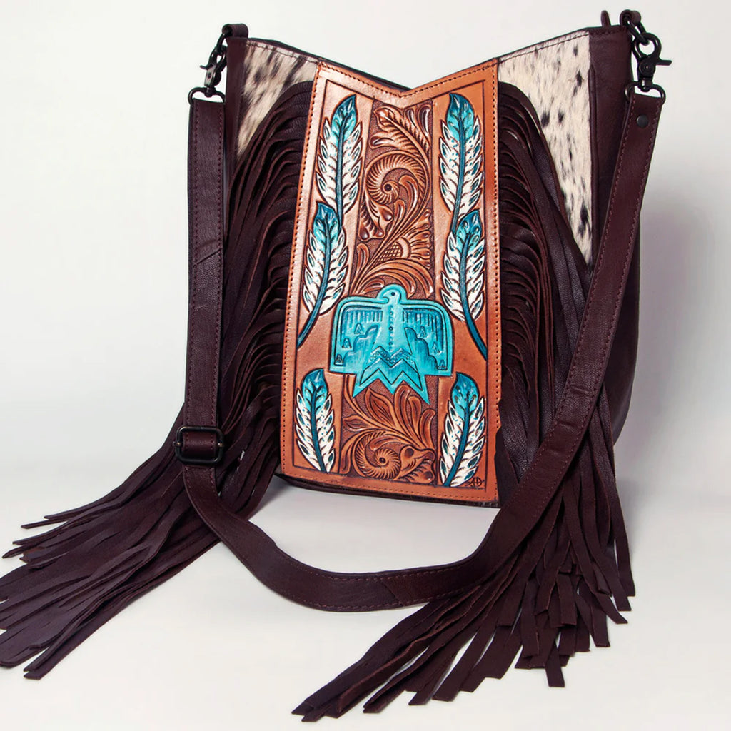 Cowhide, leather, and fringe purse with turquoise feathers and thunder bird on the front.