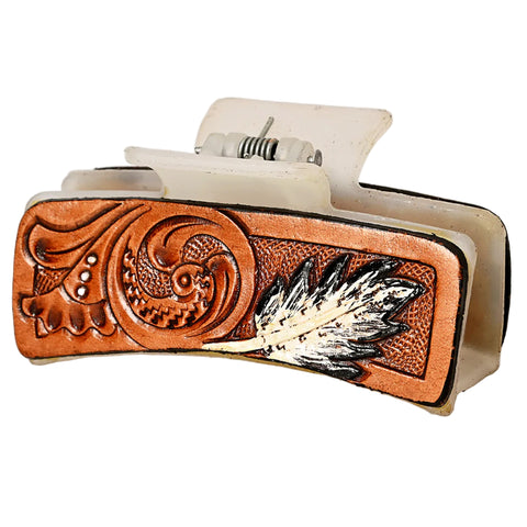 White acrylic hair clip with a tooled leather panel with a feather. 