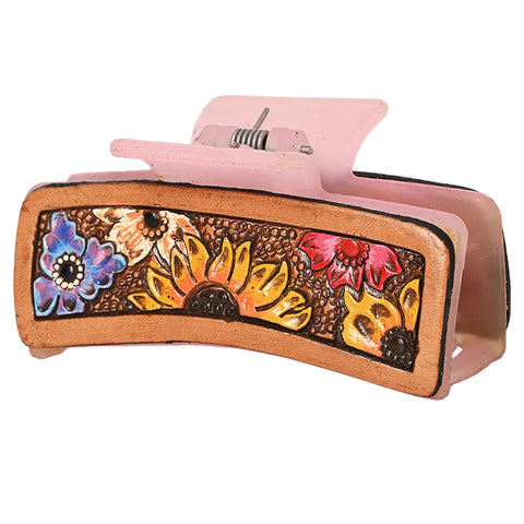 pink plastic hair clip with leather panel on the side with flower tooling. 