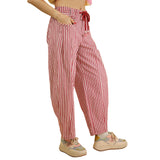 Side view of a model wearing red and white striped pants, highlighting the flowy silhouette, vertical stripes, and comfortable mid‑rise fit.
