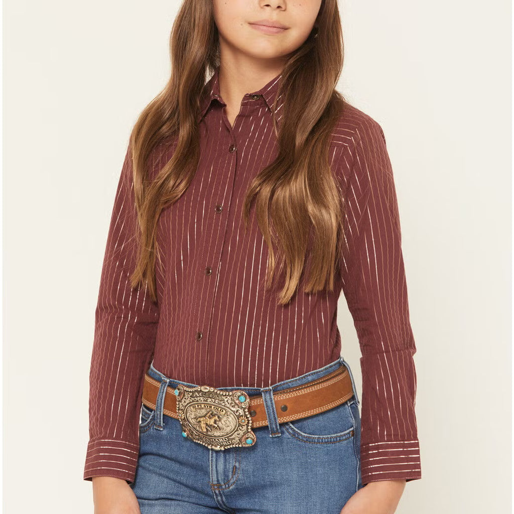 Girl Model facing the front is wearing a burgundy long sleeve pearl snap shirt. This Shirt has burgundy snaps and gold shimmer vertical stripes. 