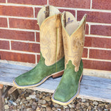 Front view of green carpincho boots against brick wall.