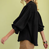 Side view of a model wearing the black 3/4 balloon sleeve blouse, highlighting the voluminous sleeve shape, smooth drape, and flattering silhouette.