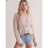 Model wearing a sand‑colored knotted cardigan sweater front view.