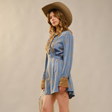 woman standing sideways wearing a Western Graphic Ruffle Tie Waist Mini Dress