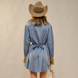 back view of a women wearing a Western Graphic Ruffle Tie Waist Mini Dress