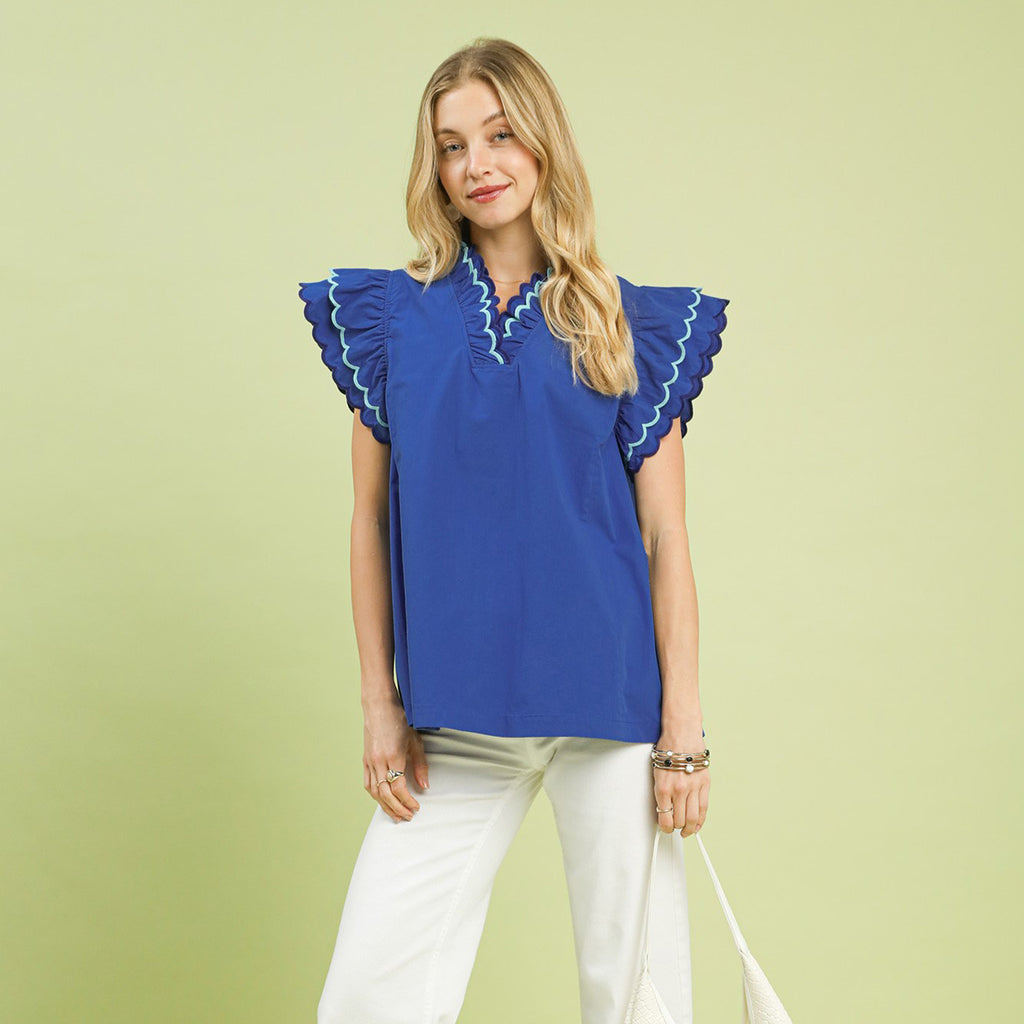 Model wearing a solid ocean blue ruffle scalloped sleeve top, front view showing the scalloped trim, ruffle sleeves, and Western‑inspired feminine style.