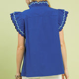 Back view of model wearing a solid ocean blue ruffle scalloped sleeve top showing the smooth back and easy, flowy fit.