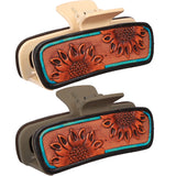 Close‑up of the sunflower tooled leather hair clip focusing on the detailed sunflower tooling and turquoise accents in both colors