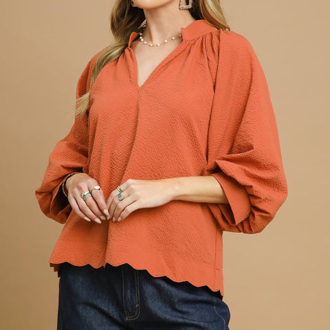 Rust colored v neck shirt with 3/4 length puff sleeves. 