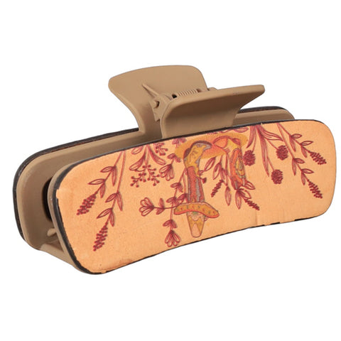 Tan plastic claw clip with leather overlay on the sides with wild flower and cowboy boot print.