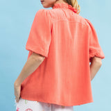 Back view of model wearing a coral linen scallop V‑neck puff sleeve top showing the smooth back and relaxed, feminine fit.
