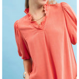 Close‑up of model wearing a coral linen scallop V‑neck puff sleeve top focusing on the scalloped neckline, puff sleeve detail, and textured linen fabric.