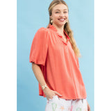 Side view of model in a coral linen scallop V‑neck puff sleeve top highlighting the puff sleeve shape and airy linen drape.