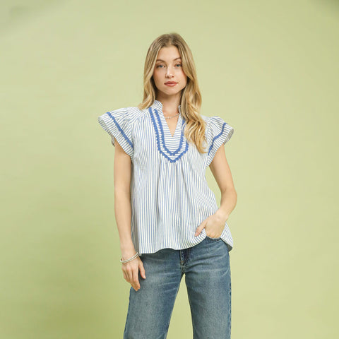 Model wearing a blue striped scalloped trim flutter sleeve top, front view showing the scalloped neckline and soft flutter sleeves.