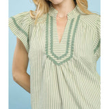 Close‑up of model wearing the sage striped scalloped trim flutter sleeve top focusing on the scalloped trim and striped fabric texture.