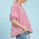 Side view of model in a raspberry and white striped puff sleeve babydoll top highlighting the puff sleeve shape and relaxed drape.