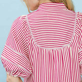 Close‑up of model wearing a raspberry and white striped puff sleeve babydoll top focusing on the striped fabric