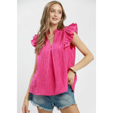 Front view of model in fuchsia textured V‑neck top with ruffle sleeve detail.
