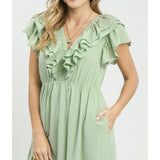 Close‑up of model wearing a sage textured ruffle tiered midi dress focusing on the textured fabric and ruffle sleeve detail.