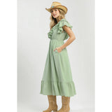 Side view of model in a sage textured ruffle tiered midi dress highlighting the tiered movement and soft ruffle sleeve detail.