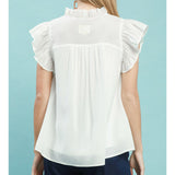 Back view of model wearing an off‑white smocked yoke ruffle sleeve blouse showing the smooth back panel and easy, feminine fit.