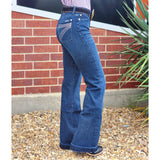 Person wearing blue jeans with decorative seven stud design on back pocket.