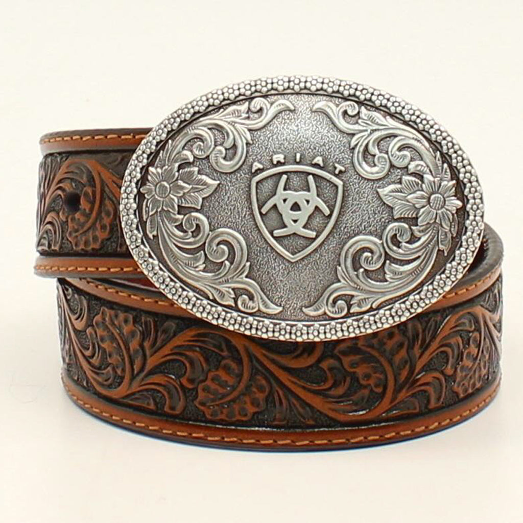 It features a beautiful floral embossed tan leather strap set off by a detailed oval removable silver buckle with raised Ariat shield logo and floral accents.

