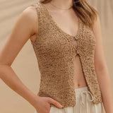 Close up view of sand colored crocheted vest with two top buttons.