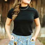 Woman wearing a black top and blue patterned skirt with a blurred background