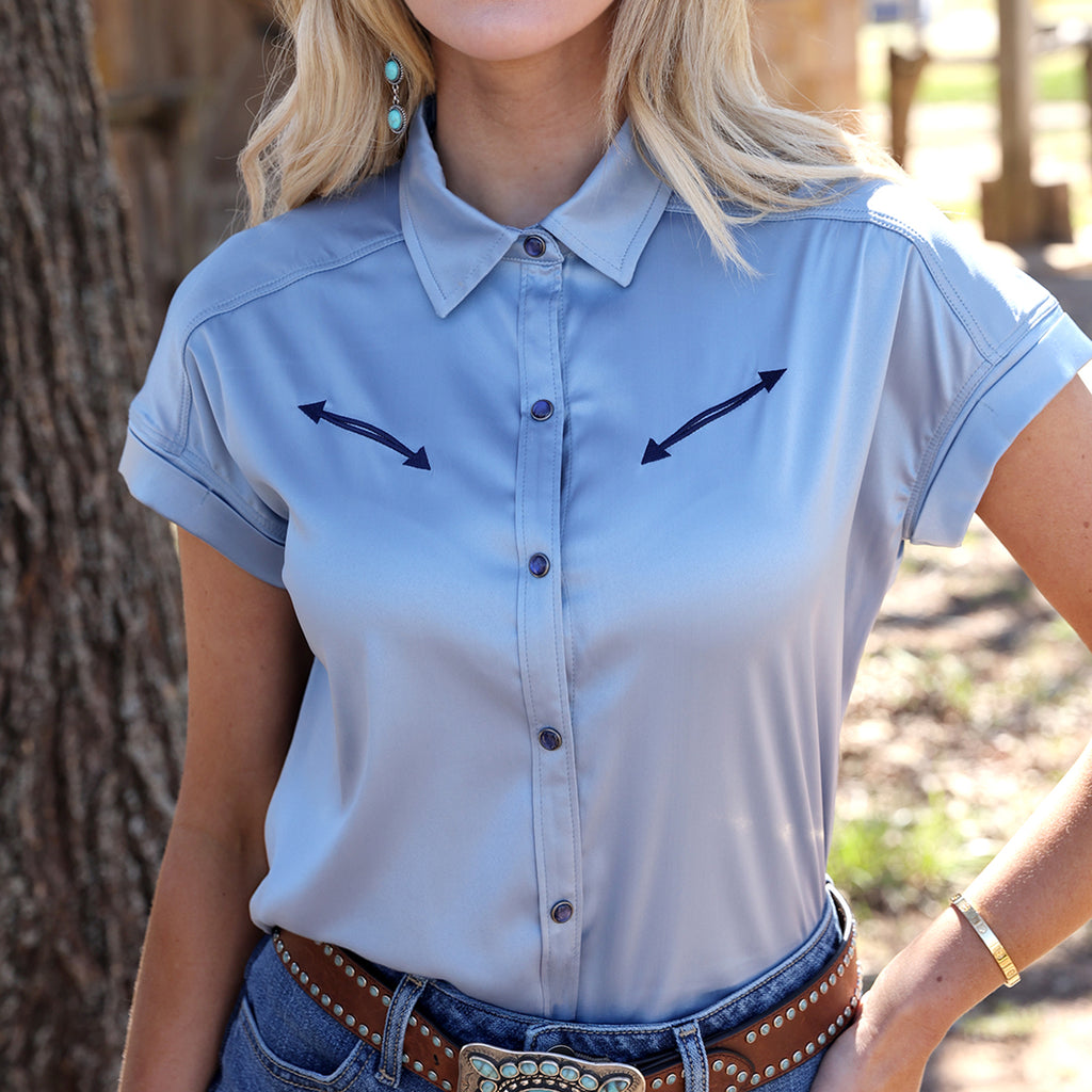 Model wearing light blue satin shirt tucked into jeans and front facing. 