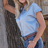 Model side facing wearing tucked in blue satin shirt. 
