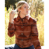 Close-up of a red jacquard print Western jacket showing the patterned fabric, studded shoulder yoke, spread collar, and snap closure.