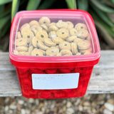 Red container filled with coconut ring horse treats on a wooden surface