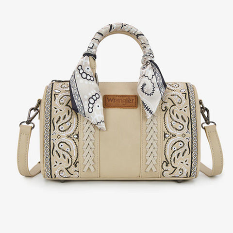 Medium sized tan barrel shaped purse with white and black paisley printed on the sides. Purse has two short straps with a bandana wrapped around one and a long crossbody strap. 
