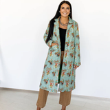 Woman wearing a turquoise color patterned coat on a white background