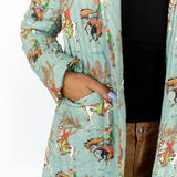 Person wearing a turquoise quilted jacket with vintage-style horse and rider print.