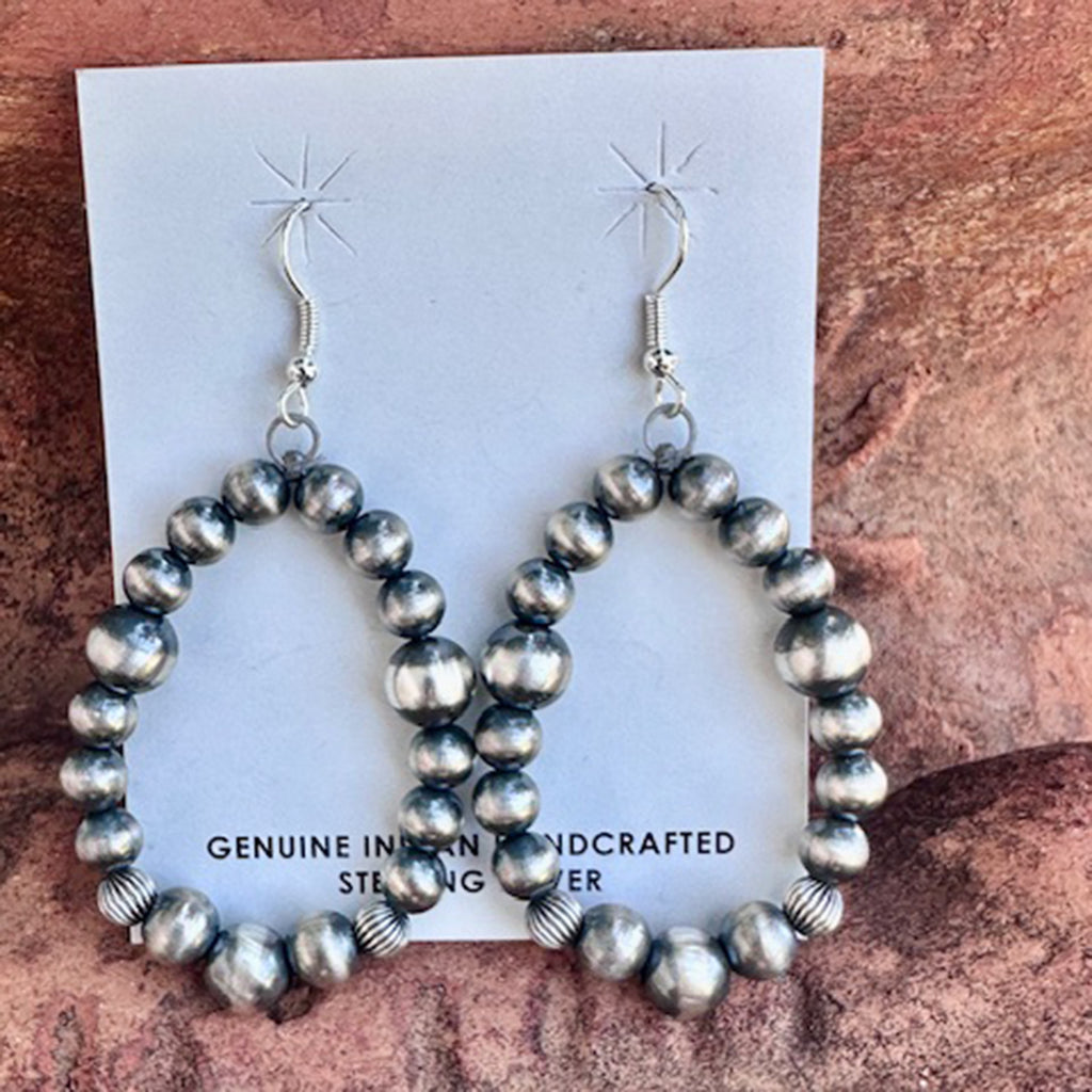 Hoop earrings with silver beads on a card with text on a textured surface