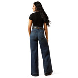 Back view of women wearing dark wash denim jeans with back square pockets and a black shirt.