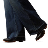Dark wide leg jeans with black boots on a white background.