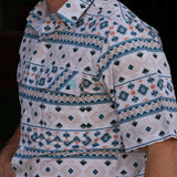 Close up side view of the tan, white, and teal short sleeve shirt 