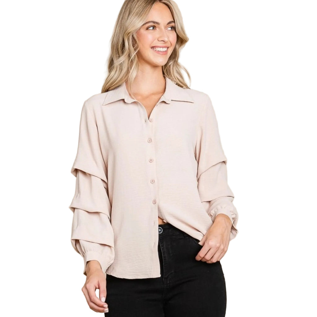 Woman wearing a tan blouse with tiered ruffled sleeves