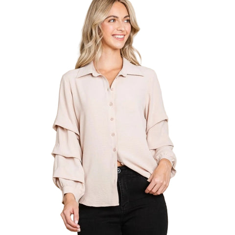 Woman wearing a tan blouse with tiered ruffled sleeves