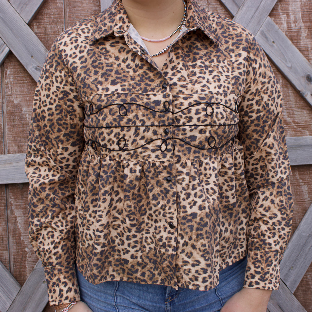 Leopard print long sleeve button up with black pearl snap closure down the middle and black loopty design across the chest.